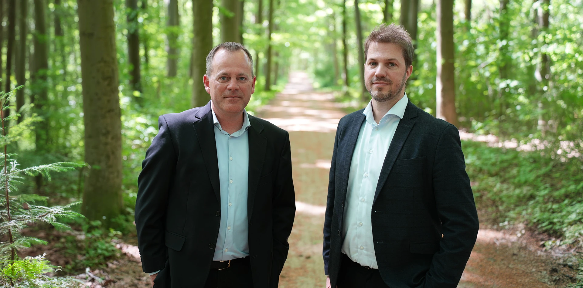 Peter og Michael fra Log Advisor står i en skov, for at symboliserer deres miljømæssige ansvarlighed